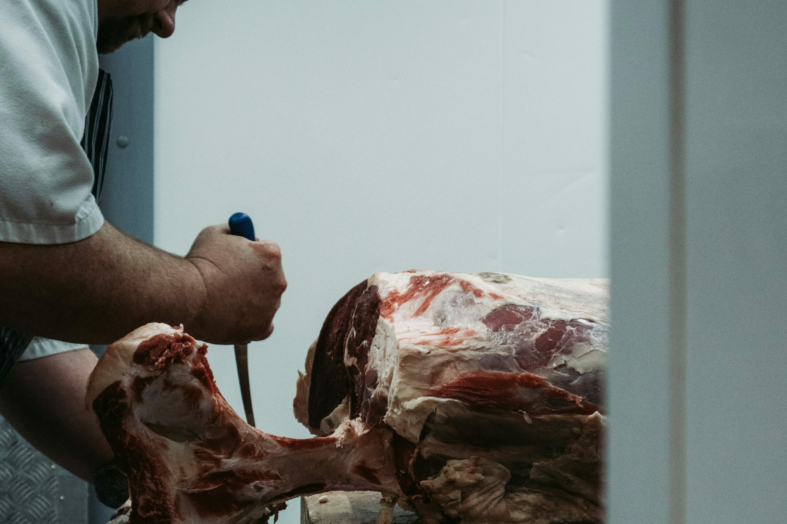 Artisan boucher découpant une pièce de bœuf à l’herbe, illustrant les points de vente du réseau Bœuf Herbe