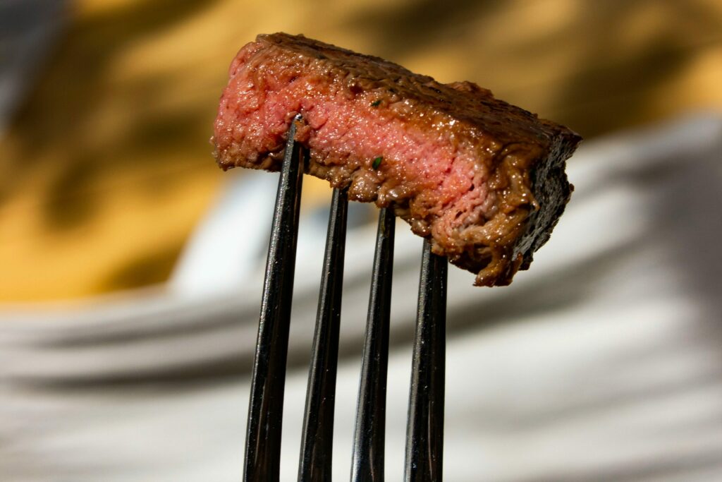 Morceau de bœuf à l’herbe saisi à point, tenu sur une fourchette, illustrant la cuisine simple et savoureuse des restaurants du réseau
